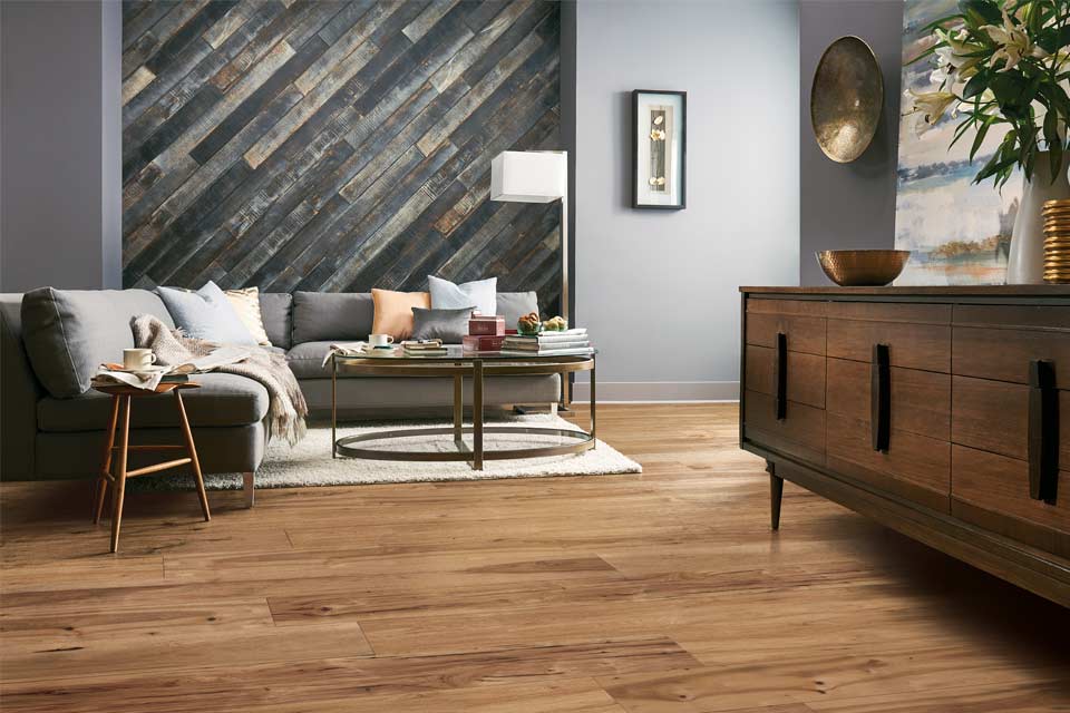 wood flooring in living room with grey couch and wood cabinet with cold and blue decor.